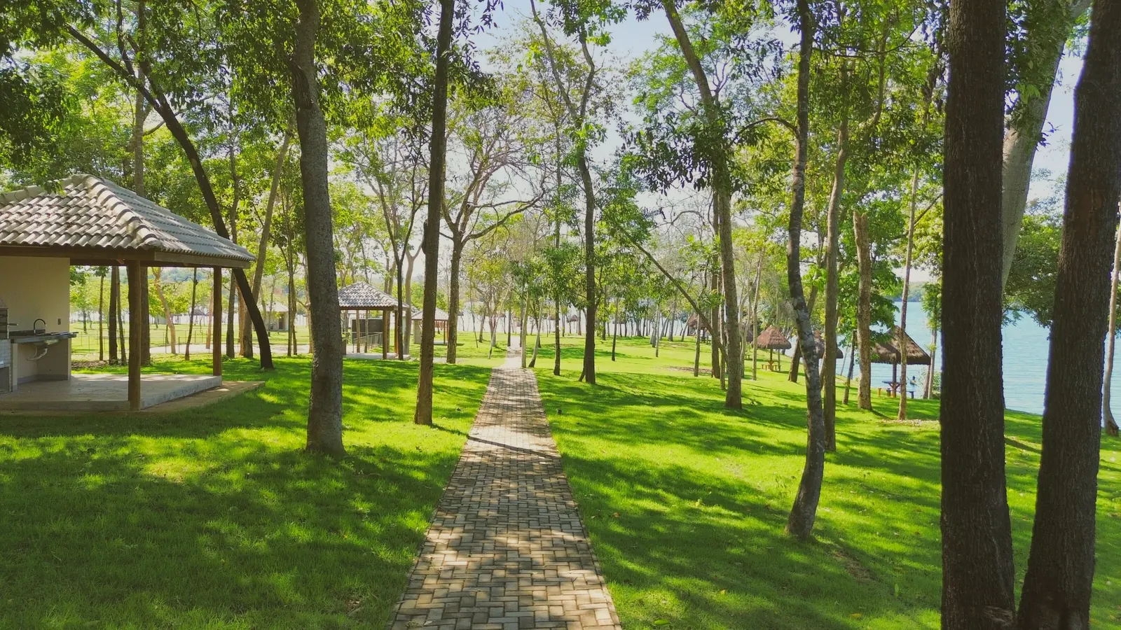 Caminho de blocos entre as árvores do bosque do Quinta do Lago, com um quiosque com churrasqueira ao lado